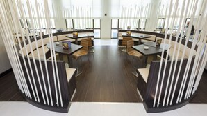 A modern dining area with round tables and chairs, a central light fixture, and tall decorative elements. - ibis Tunis (Tunis)