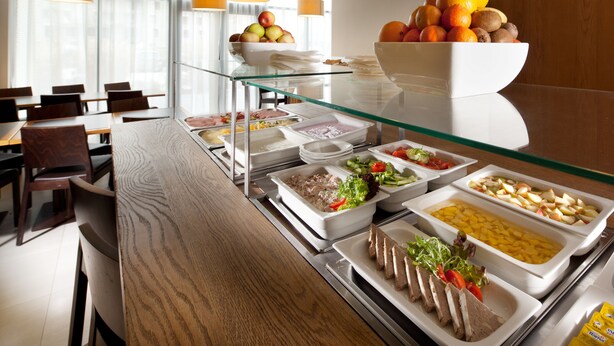 A buffet setup with various food items and a glass display case. - Comfort Hotel Olomouc Centre (Olomouc)