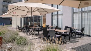 An outdoor patio with tables and chairs, large umbrellas, and a brick floor. - Comfort Hotel Olomouc Centre (Olomouc)