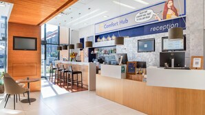 A reception area with a reception desk, chairs, a bar, and a large window. - Comfort Hotel Olomouc Centre (Olomouc)