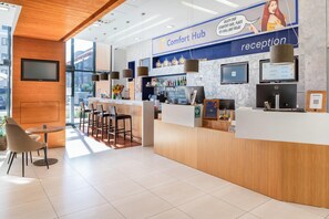 A reception area with a reception desk, chairs, a bar, and a large window.