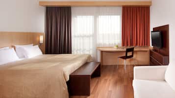 Una habitación de hotel con una cama, un escritorio, un televisor y un sofá.