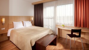 A hotel room with a bed, bedside table, desk, chair, and a window with curtains. - Comfort Hotel Olomouc Centre (Olomouc)