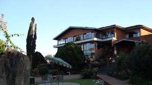 Een hotel met een zwembad, terras en een goed onderhouden tuin.