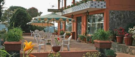 A restaurant patio with outdoor seating, potted plants, and a sign reading "GALLIMORO".