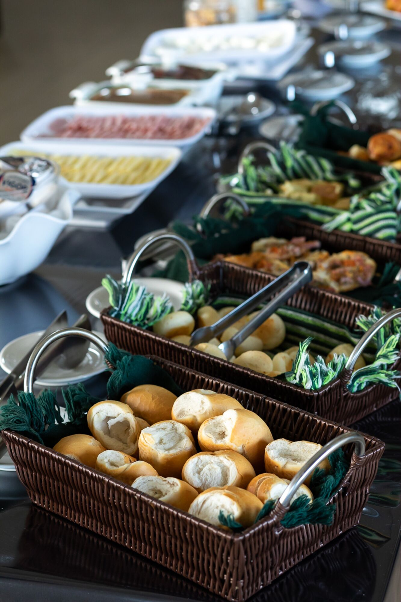 A buffet with various food items including bread rolls, vegetables, and other dishes.