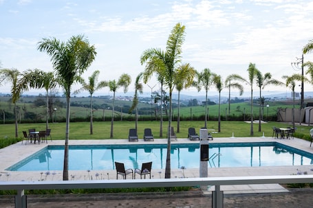 Una piscina al aire libre, sillones reclinables de piscina