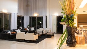 A modern living room with a sectional sofa, a coffee table, and a decorative vase with plants. - Class Hotel Passos Rio Grande Portal da Canastra (Passos)