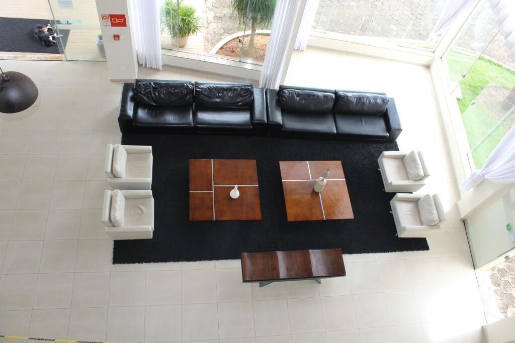 Ein modernes Wohnzimmer mit einem schwarzen Ecksofa, weißen Sesseln und einem Couchtisch.