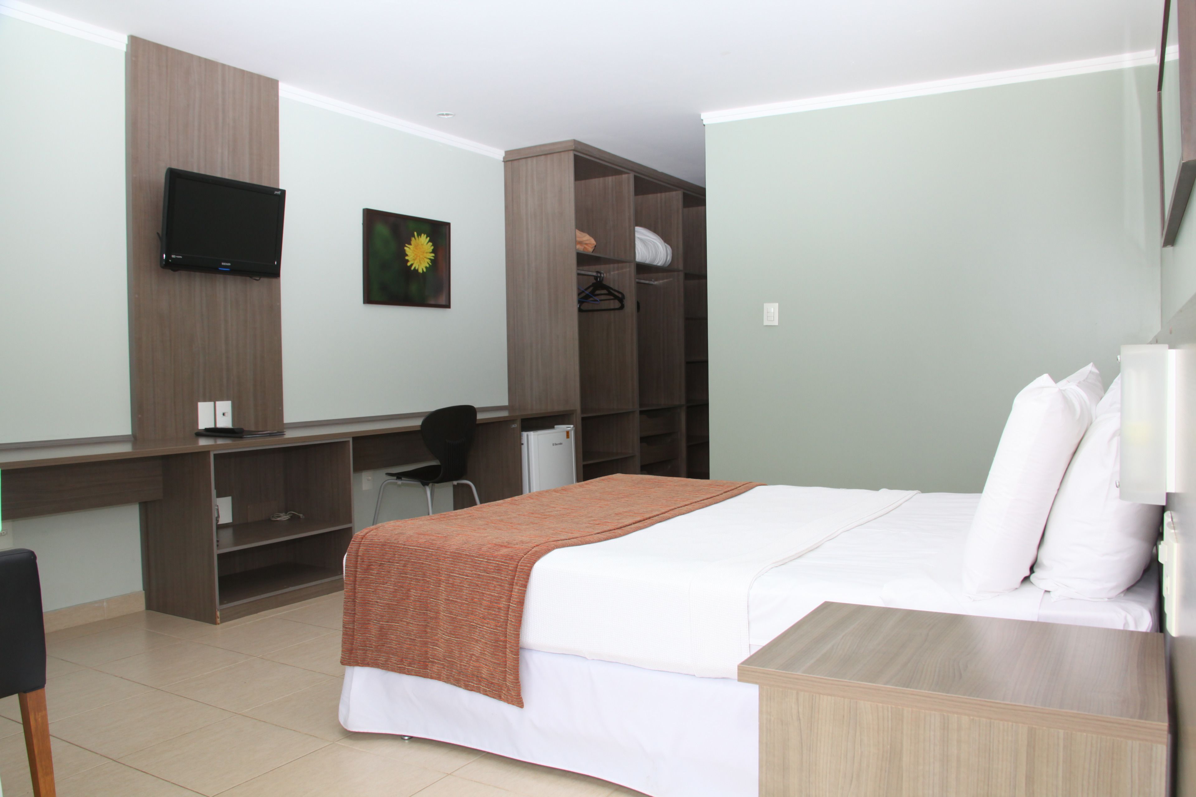 Une chambre d’hôtel équipée d’un lit, d’un bureau, d’une chaise, d’une télévision et d’une armoire.