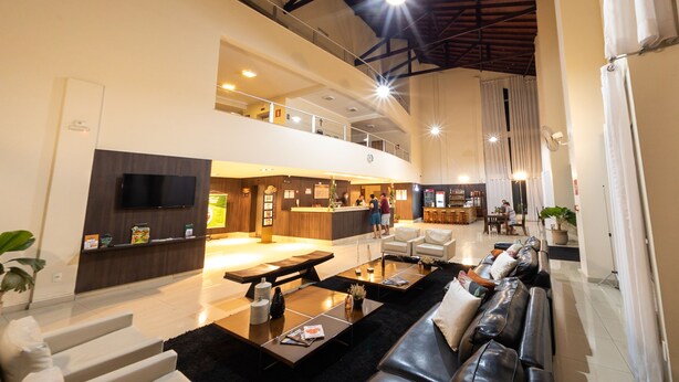 A spacious lobby with a reception desk, seating area, and a staircase leading to an upper level. - Class Hotel Passos Rio Grande Portal da Canastra (Passos)
