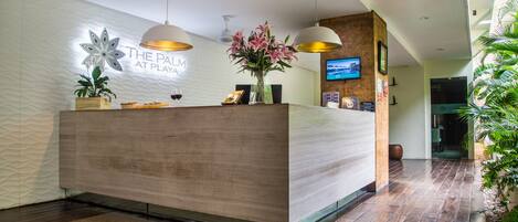 A reception desk with a modern design, a wall-mounted sign, and a television screen.