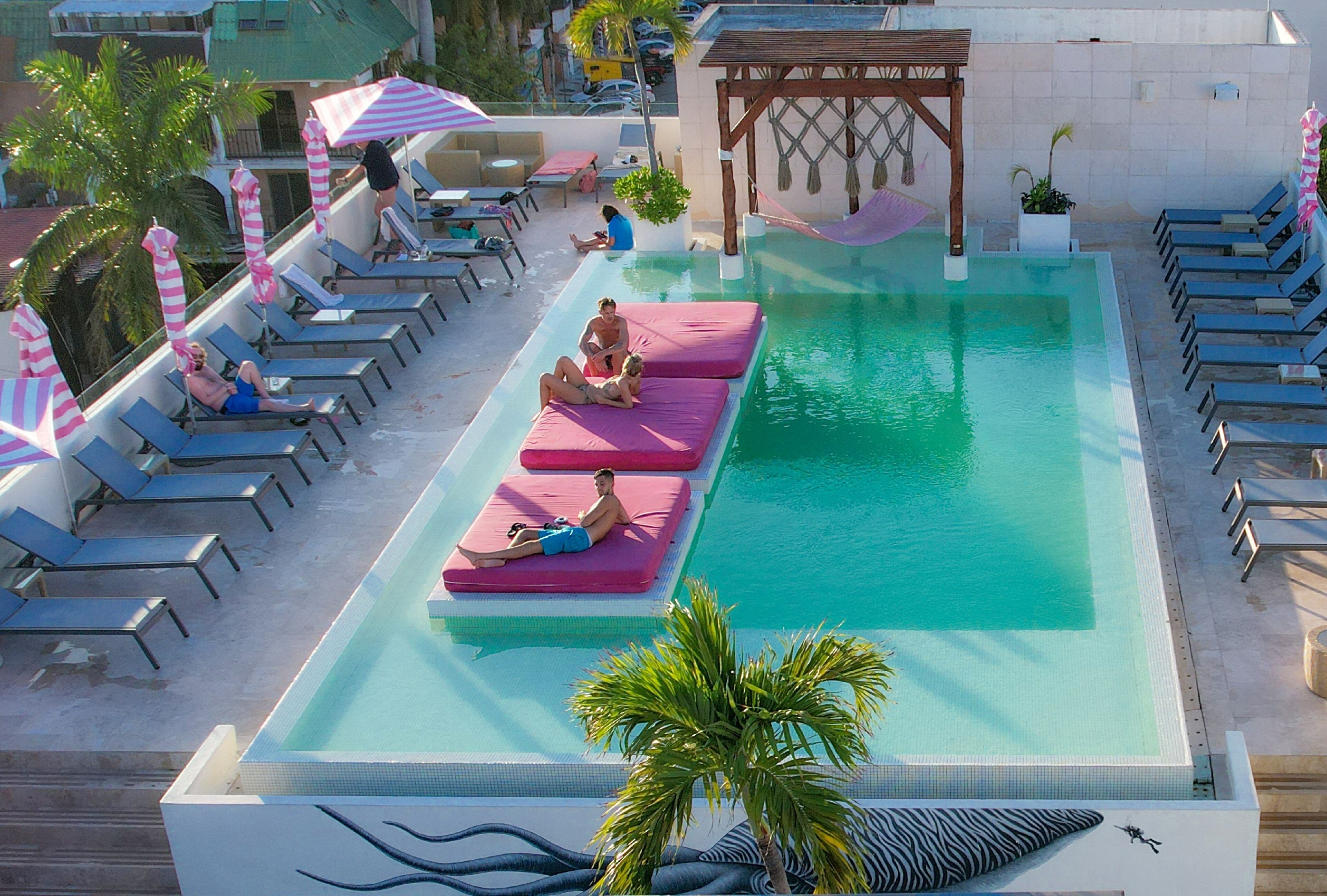 A pool area with lounge chairs and sunbeds, a small slide, and a pergola with a hammock.