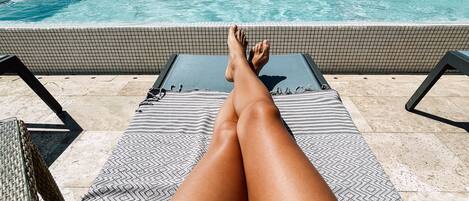 Un espace de détente aménagé au bord de la piscine, avec un sol carrelé, des chaises longues et une piscine.