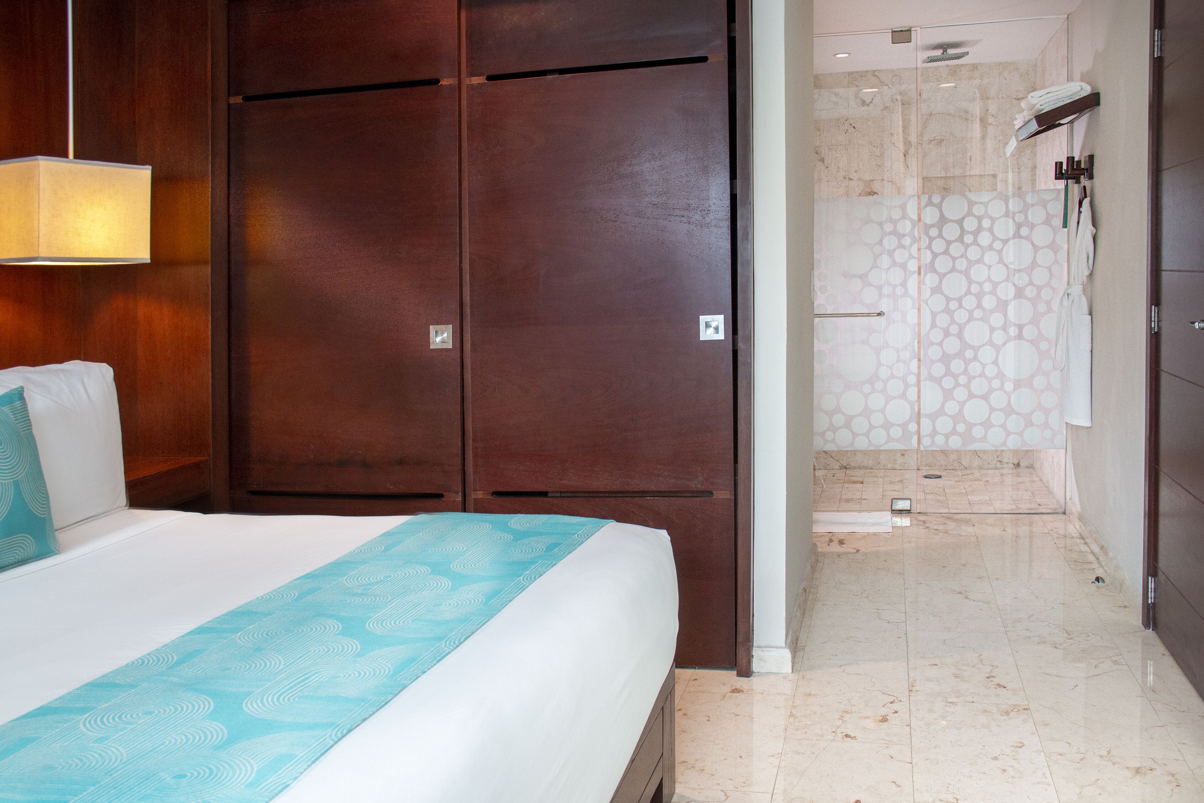 A hotel room with a large bed, a wardrobe, and a shower area.