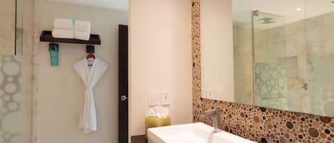 Un baño moderno con un espejo grande, un lavamanos blanco y un perchero para toallas.