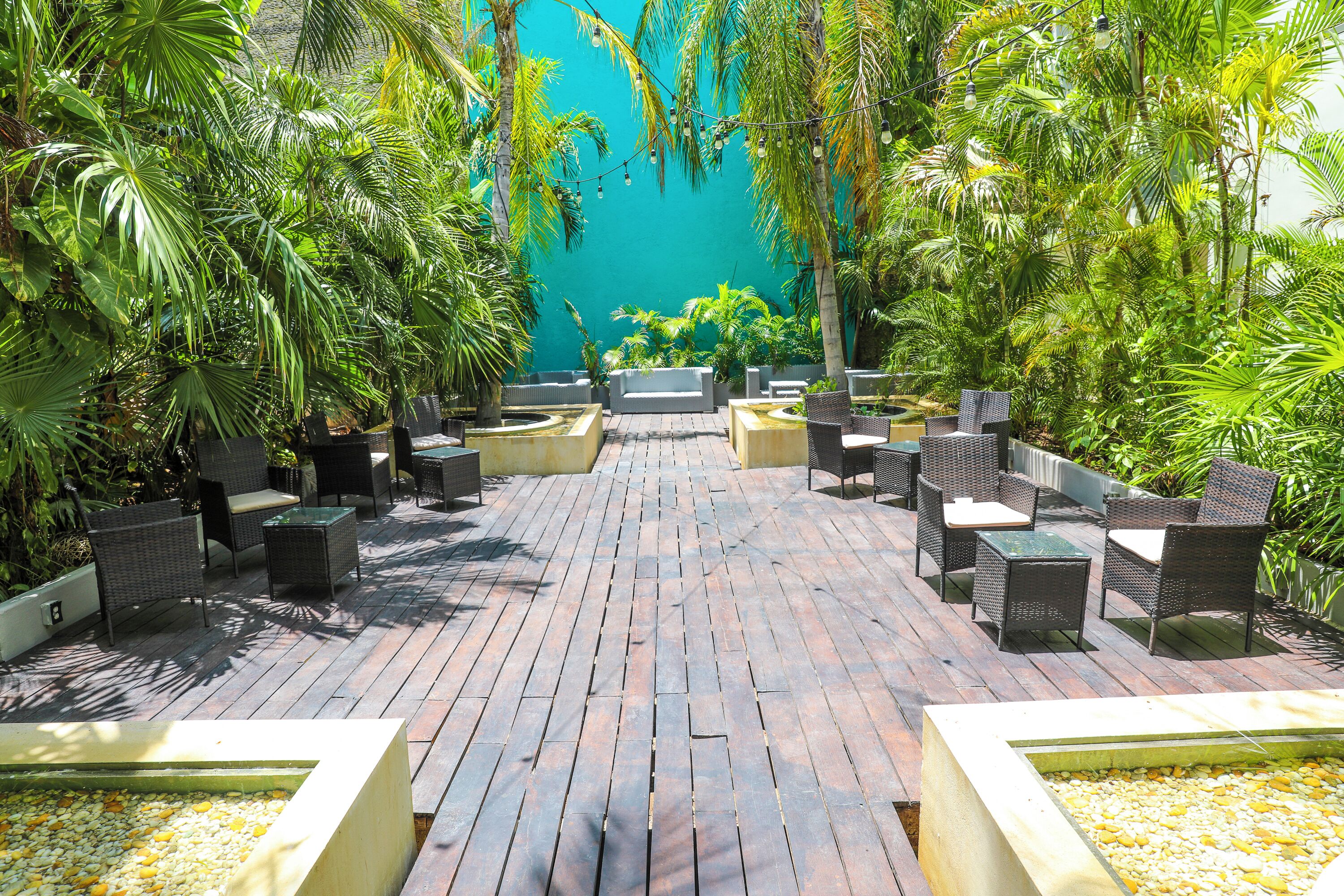 An outdoor patio with wicker furniture, a pathway, and lush greenery.