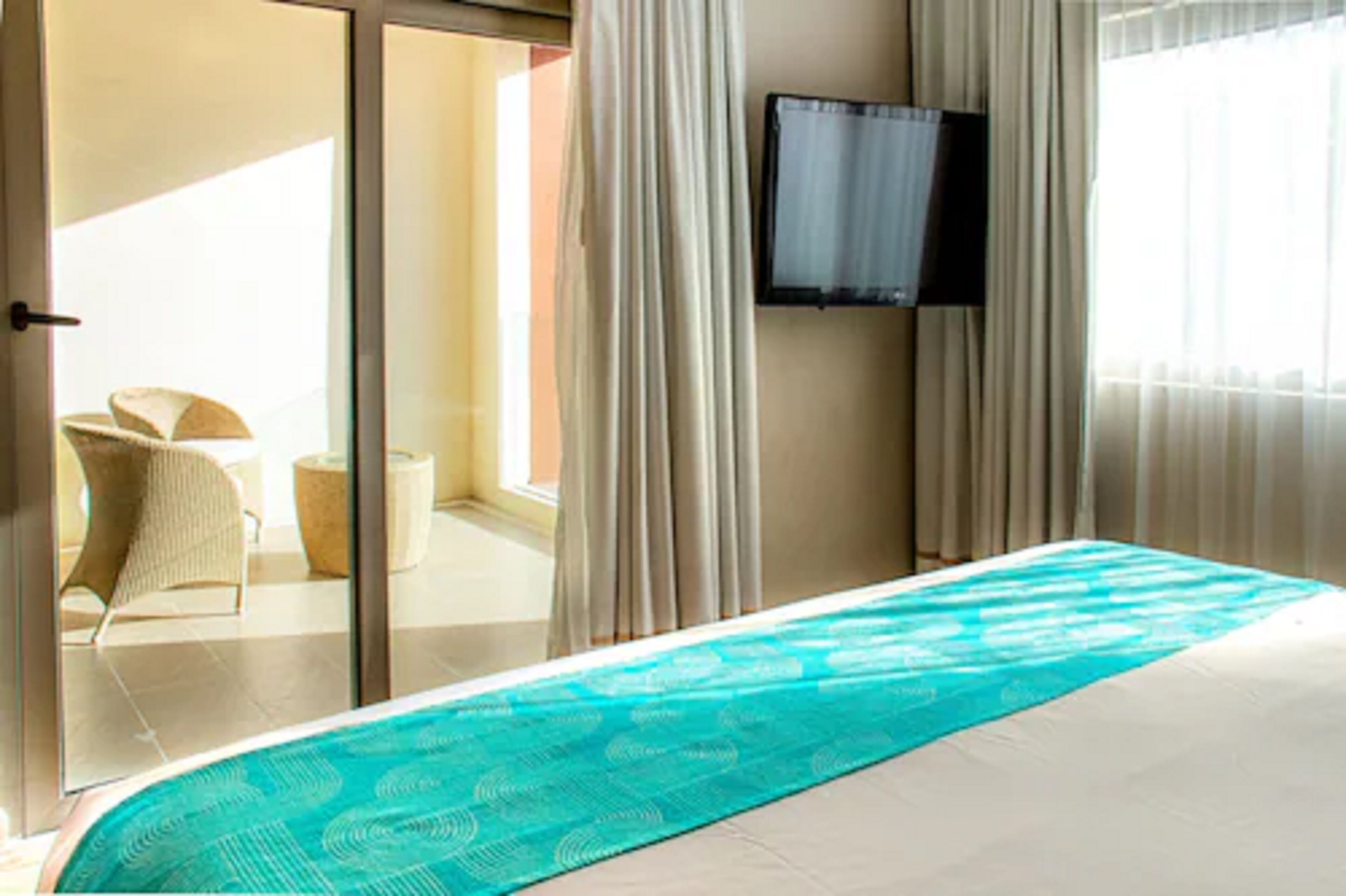 Quarto de hotel com uma cama, televisão na parede e vista para o exterior.
