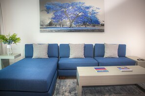 Una sala de estar moderna con un juego de sofá azul, una mesa de centro y un cuadro de un árbol.