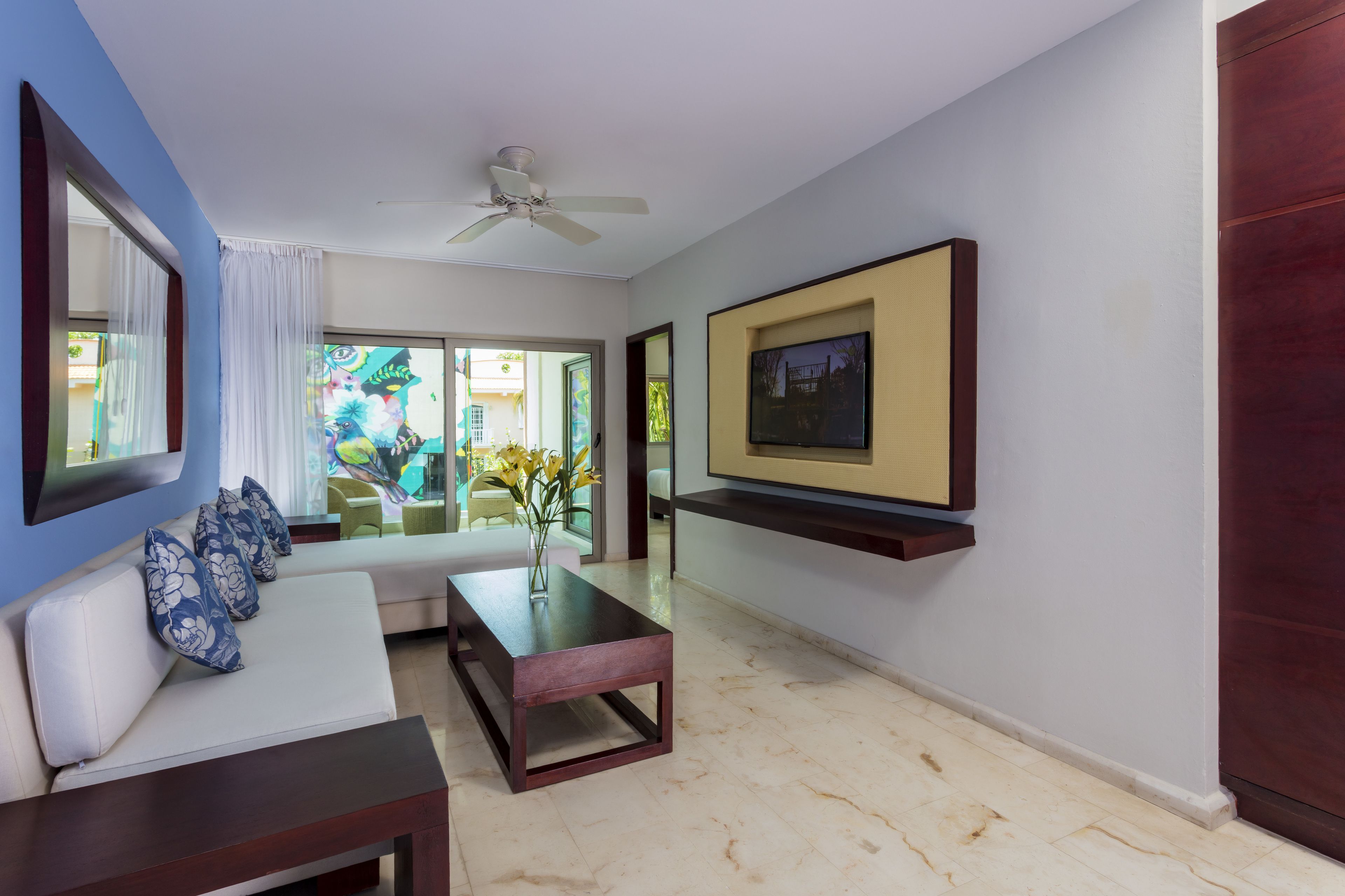 A modern living room with a sofa, coffee table, and a flat-screen TV mounted on the wall.