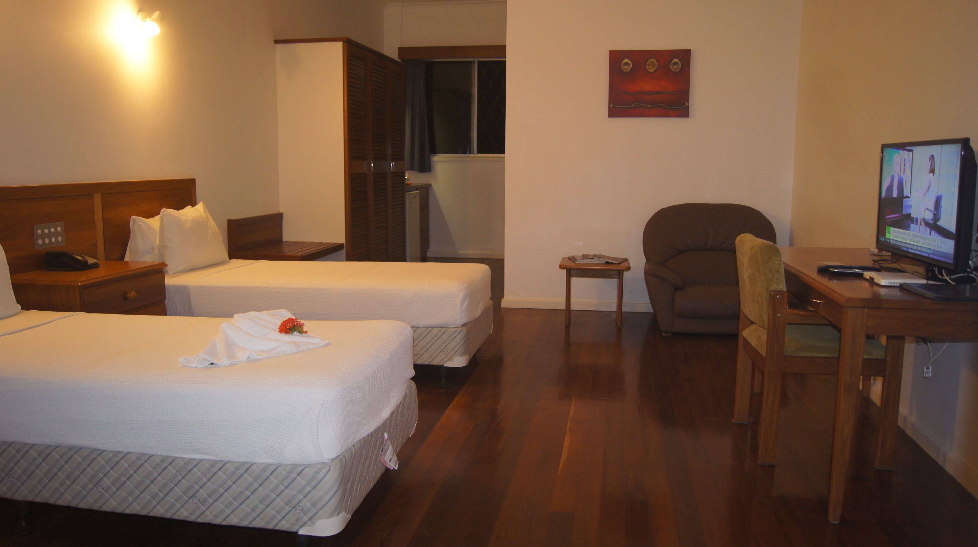 Habitación de hotel con dos camas, un escritorio con computadora, una silla y una mesita.