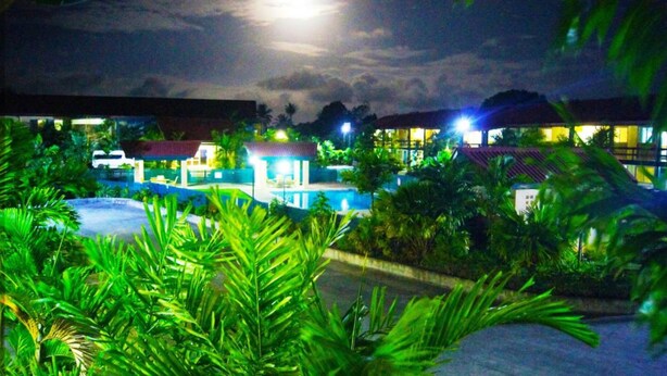 A resort with a pool, palm trees, and buildings with illuminated windows.