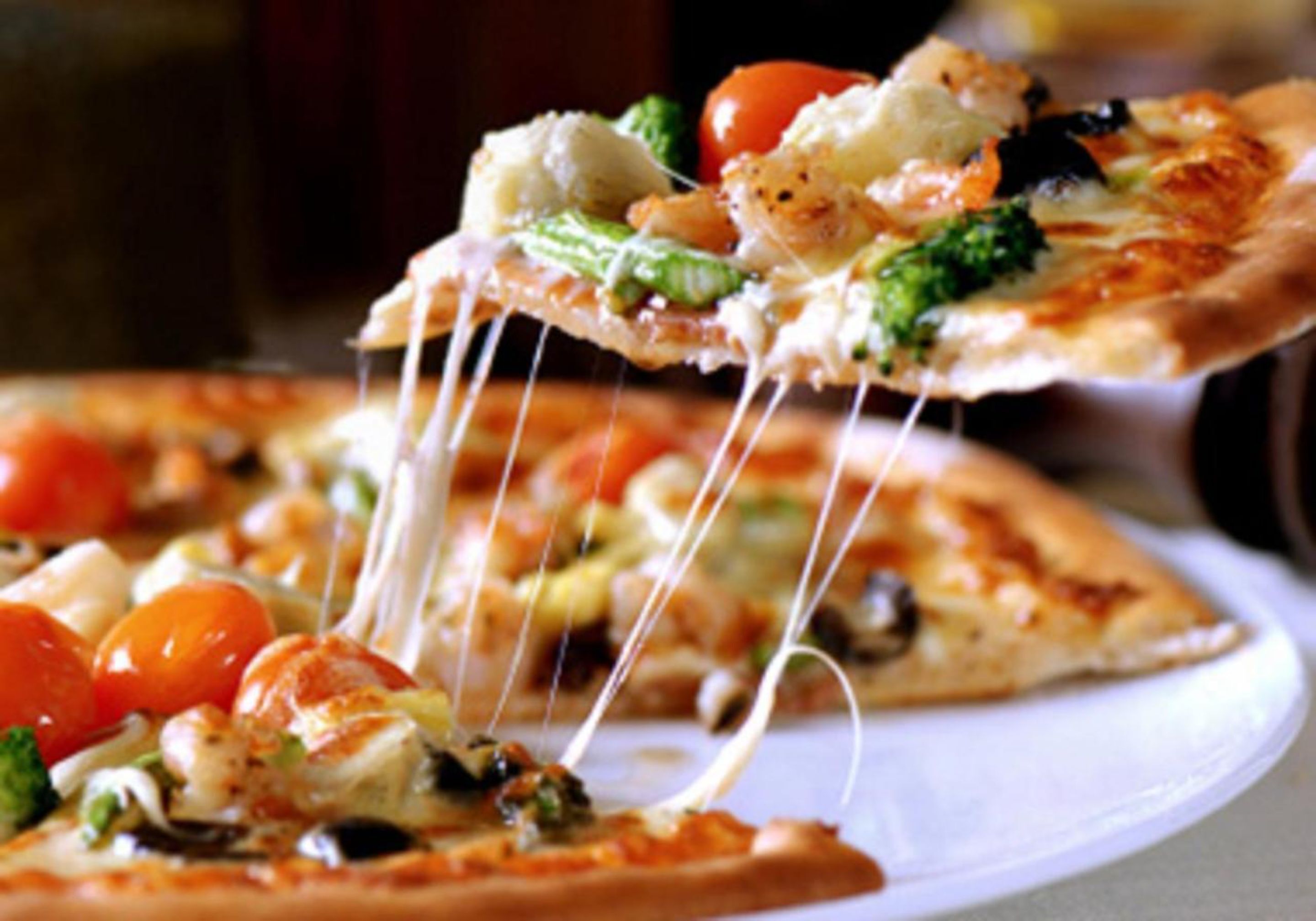 A pizza with visible toppings like broccoli, tomatoes, and cheese.