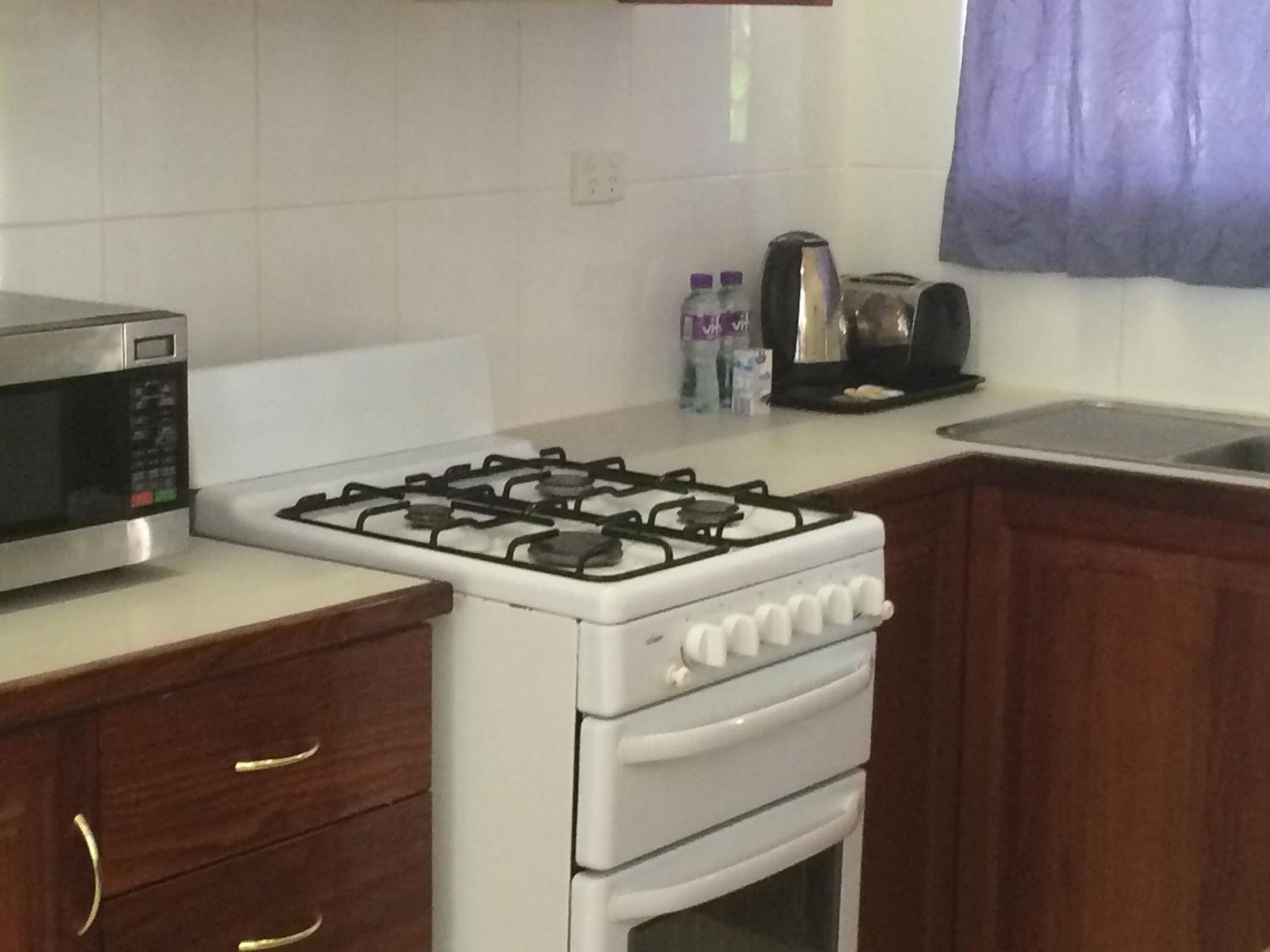 A kitchen with a stove, microwave, and wooden cabinets.