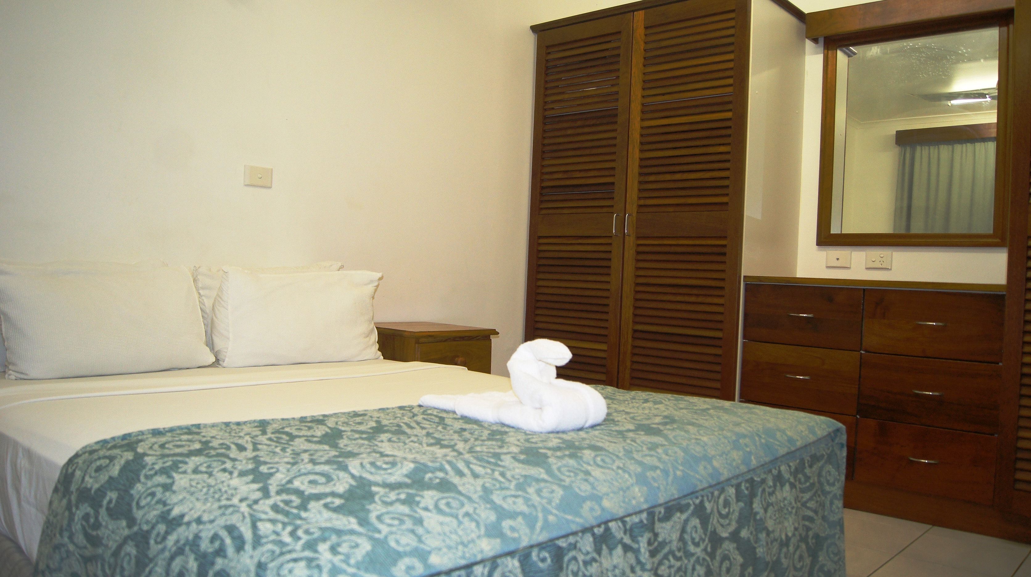Un dormitorio con una cama, un armario de madera y un espejo.