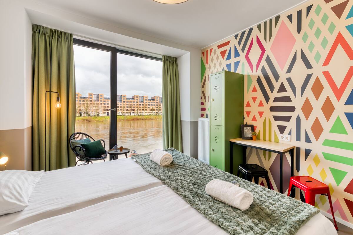 Une chambre d’hôtel équipée d’un lit, d’un bureau, d’une chaise et offrant une vue sur un plan d’eau.