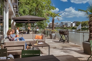 Un patio al aire libre con asientos, una parrilla y vistas al agua.