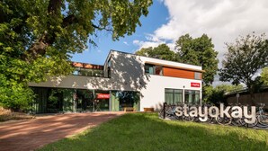 A modern building with a 'stayokay' sign, a bike parking area, and a paved walkway. - Stayokay Maastricht - Hostel (Maastricht)