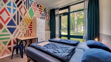 Una habitación con dos camas, un escritorio y un llamativo diseño geométrico en la pared.