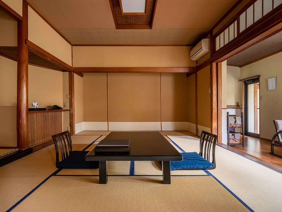 Ein traditioneller japanischer Raum mit Tatami-Böden, einem niedrigen Tisch und Holzmöbeln.