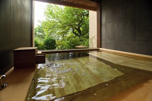 A wooden bath with a view of greenery outside.