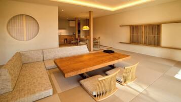 Una sala de estar moderna con una mesa de comedor de madera, sofás acolchados y suelo de tatami.