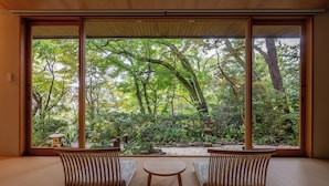 A traditional Japanese room with tatami flooring, a low table, and two wooden chairs. - Jinya Ryokan (Hadano)