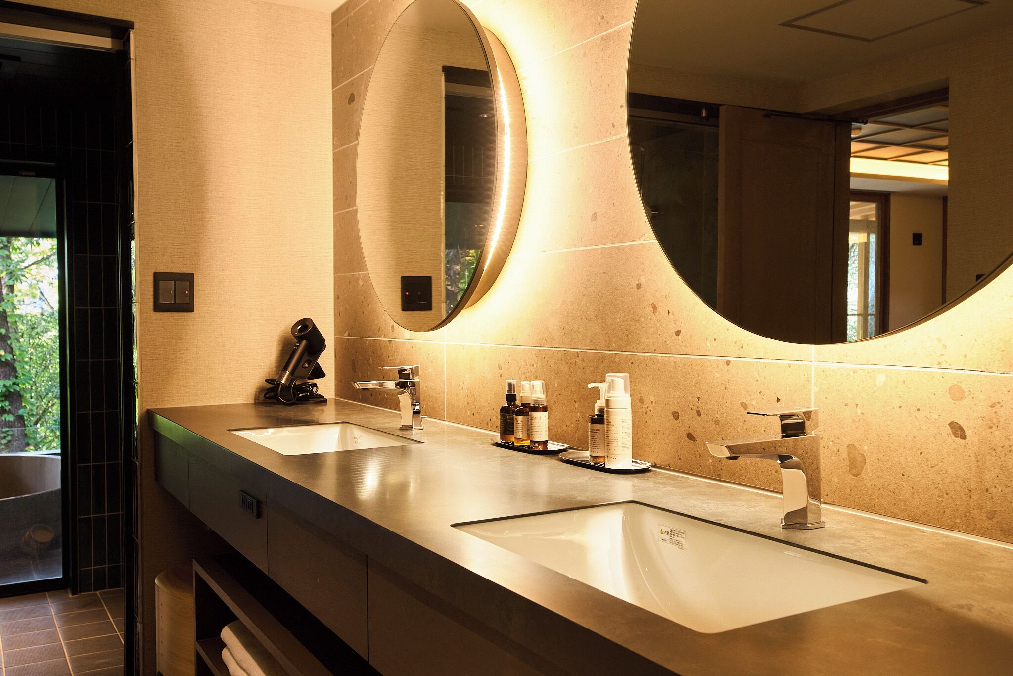 A modern bathroom with two sinks, a large mirror, and a towel rack.