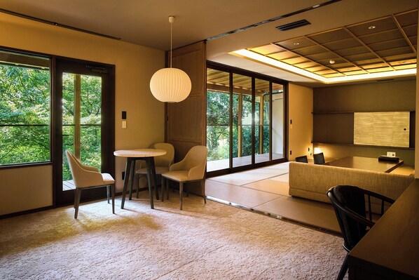 A modern room with large windows, a tatami mat floor, a low table, and a sofa.