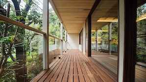 A wooden deck with glass railings overlooking a forested area. - Jinya Ryokan (Hadano)