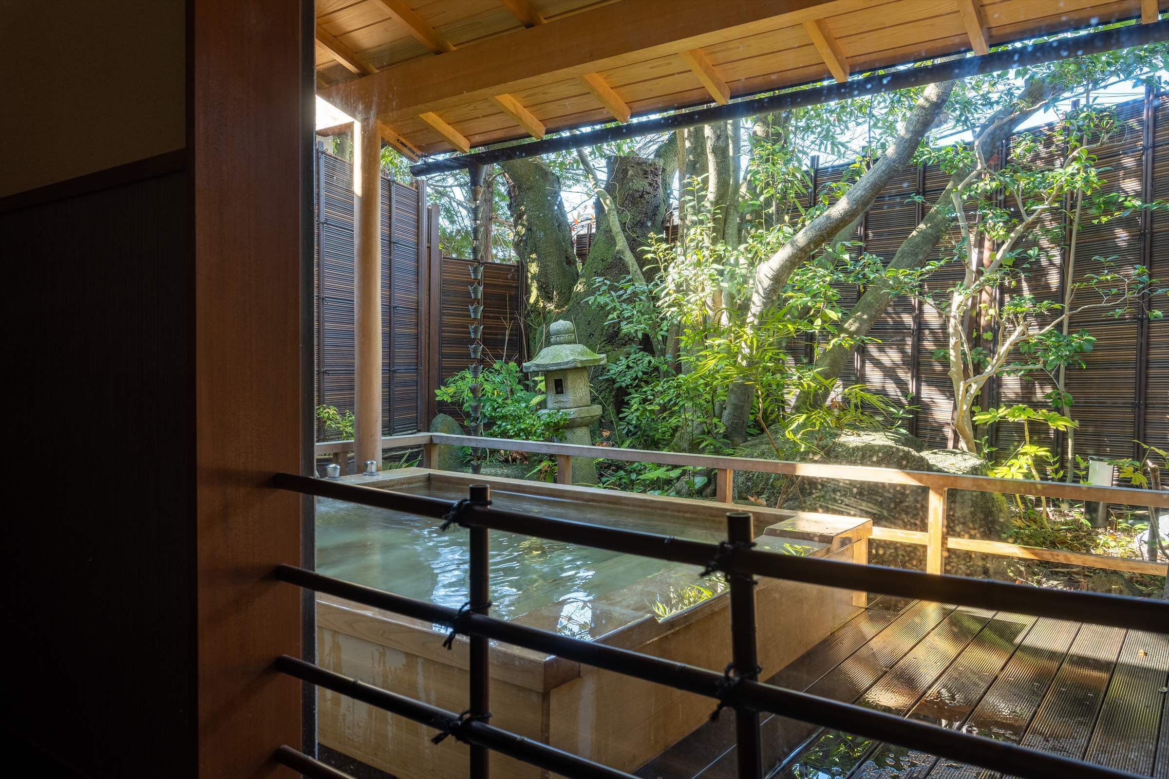 A traditional Japanese garden with a wooden deck, a stone lantern, and a koi pond.