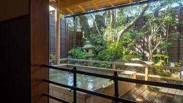 A traditional Japanese garden with a wooden deck, a stone lantern, and a koi pond.