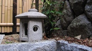 A stone lantern in a garden with bamboo and rocks. - Gion Machiya (Kyoto)