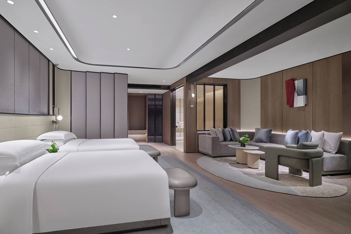 A modern bedroom with a large bed, a sofa, and a small table.