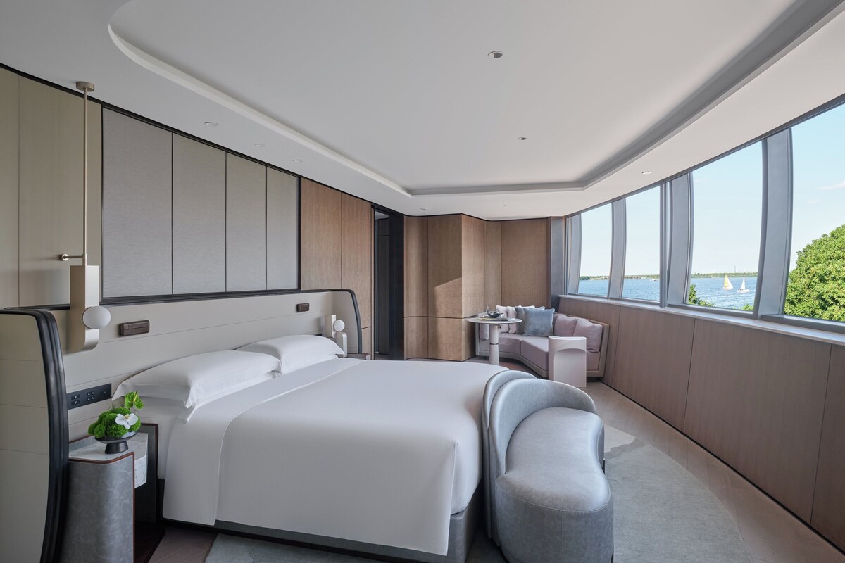 Habitación de hotel moderna con una cama grande, zona de estar y vista al mar.
