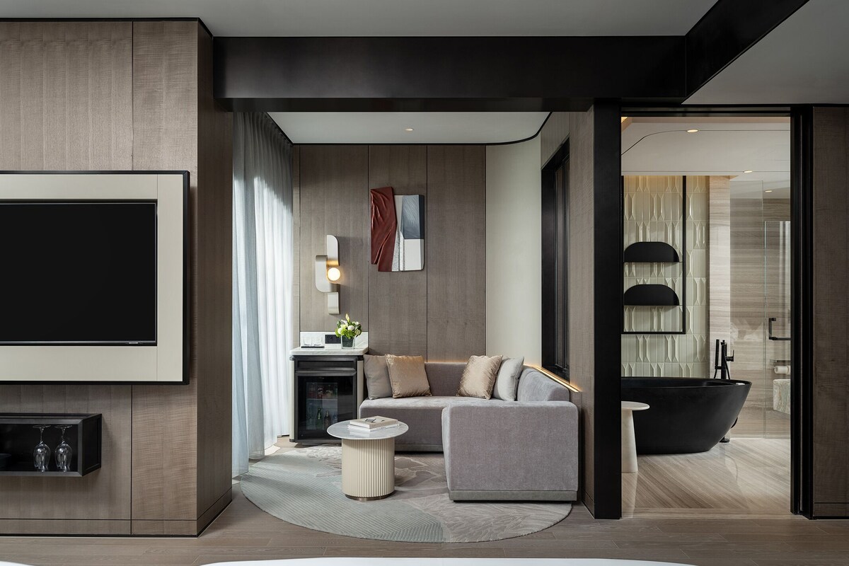Een moderne woonkamer met een flatscreen televisie, een bank, een salontafel en een open haard.
