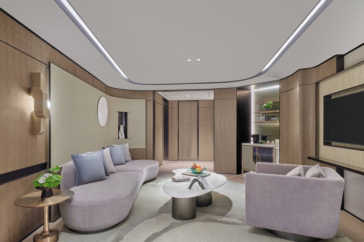 A modern living room with a sectional sofa, a round coffee table, and a flat-screen TV mounted on the wall.