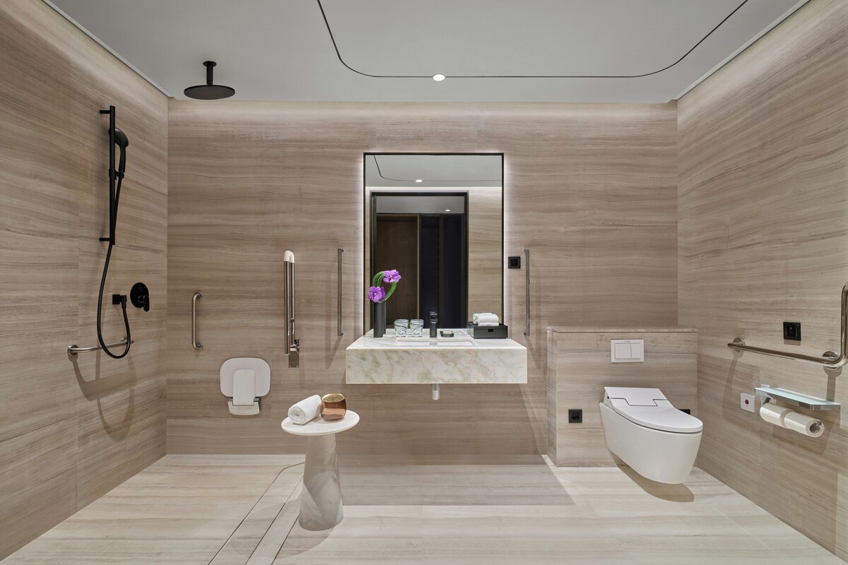 Un baño moderno con tocador de mármol, inodoro y zona de ducha.