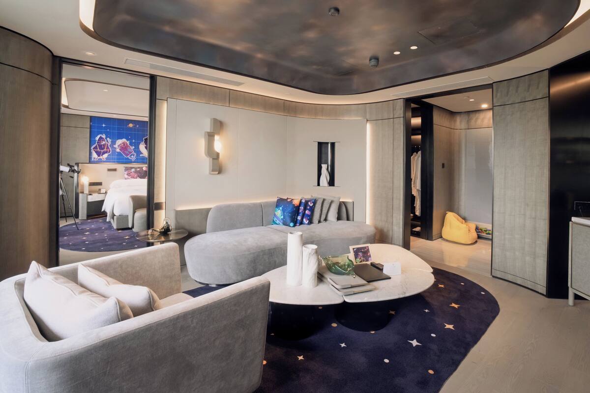 A modern hotel room with a curved ceiling, a seating area with a round coffee table, and a view of the room's interior.