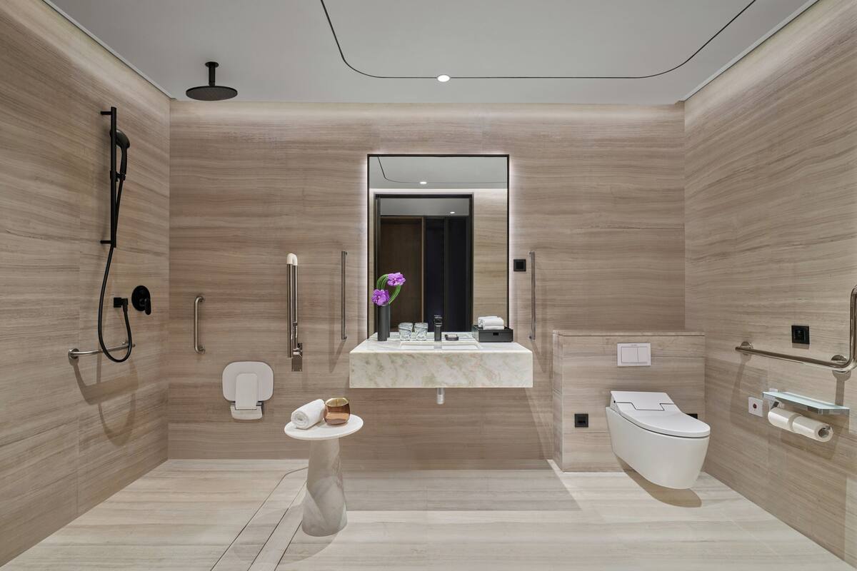 Un baño moderno con tocador de mármol, inodoro y zona de ducha.
